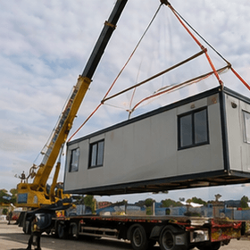 Modular building unit loaded on a flatbed truck at an offshore prefab factory, ready for shipment