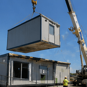 Crane lifting a modular building unit onto an offshore prefab housing factory site